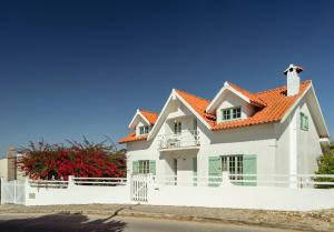 ein weißes Haus mit einem orangefarbenen Dach in der Unterkunft Charneca Caparica Casa Rey by Hopstays in Vale de Cavalos