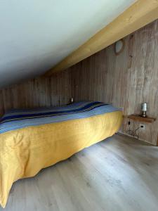 a bed in a room with a wooden wall at Le Cabanon de L'Arbey in Pierrefitte-Nestalas