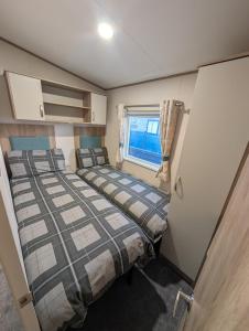 zwei Betten in einem kleinen Zimmer mit Fenster in der Unterkunft Elegant caravan home in Hampshire, United Kingdom 6 guests 2 bedroom 3 beds 1 sofa bed 2bathrooms in Hayling Island