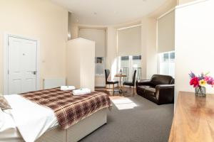 a bedroom with a bed and a desk and a chair at Victoria Court Suites - Aberdeen in Aberdeen