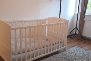 Una cuna blanca en una habitación con ventana. en Familienparadies auf dem Reiterhof, en Bad Nenndorf
