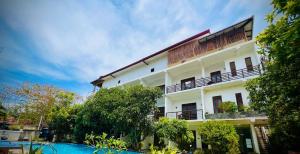 米瑞莎Wavelength Hotel & Wellness Center的一座白色的建筑,前面有一个游泳池