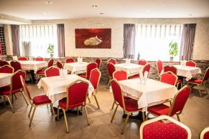 Un comedor con mesas blancas y sillas rojas. en Hostal La Corte, en Carrión de los Condes