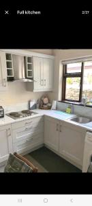 eine Küche mit weißen Schränken und einer Spüle und einem Fenster in der Unterkunft Townhouse Wexford in Wexford
