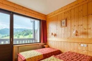 a bedroom with two beds and a large window at Résidence & Spa La Grande Cordée - Combloux in Combloux +110 photos