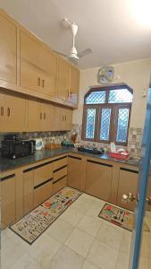 a kitchen with wooden cabinets and a large window at ZM Homestay - Luxury Comfort Awaiting in Tājganj