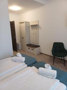 a room with two beds and a green chair at Villa Fogarasi in Târgu-Mureş