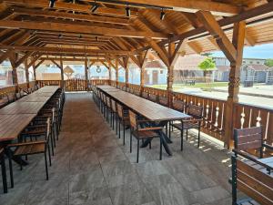 a row of wooden tables and benches in a pavilion at Hadnagy Étterem és Panzió in Lupeni