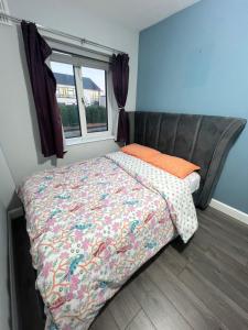 a bed with a comforter and a window in a bedroom at Happy Place in Navan
