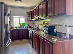 a kitchen with wooden cabinets and a stainless steel refrigerator at Stylish La Romana Apartment with 2-Way Air Con Covered Parking in Batey Río Dulce