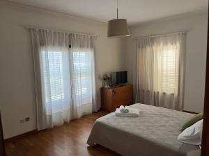a bedroom with a bed and two large windows at Quinta dos Arcos in Barcelos