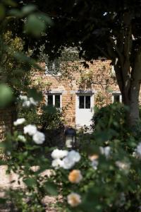 ein Backsteingebäude mit einer weißen Tür im Hof in der Unterkunft Two Rose Walk Cottage Cotswolds in Moreton-in-Marsh