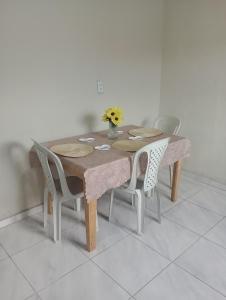 Una mesa de comedor con sillas y una mesa con flores. en Casa aconchegante, en Belém