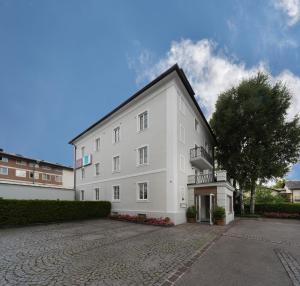 ein weißes Gebäude mit einem Balkon an der Seite in der Unterkunft Amedeo Zotti Residence Salzburg in Salzburg
