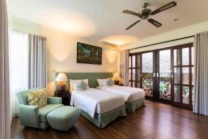a bedroom with a bed and a chair and a ceiling fan at Villa Nesanur - Comfortable & Spacious Beachside Sanur in Sanur