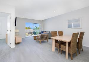 Un comedor y una sala de estar con mesa y sillas. en Pacific Blue Poolside Escape, en Salamander Bay