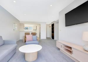 una sala de estar con un sofá y una mesa en Pacific Blue Poolside Escape, en Salamander Bay