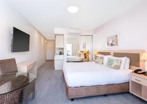 Una habitación de hotel con una cama grande y un escritorio. en Pacific Blue Poolside Escape, en Salamander Bay
