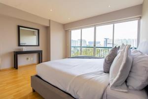 Un dormitorio con una gran cama blanca con una gran ventana. en Capitalia Luxe 1BR Stay with Top Features, en Ciudad de México