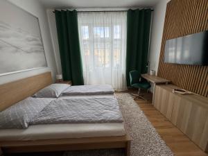 a bedroom with two beds and a desk and a window at Hotel Praděd Rýmařov in Rýmařov