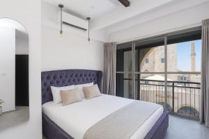 a bedroom with a bed and a large window at Safra - Boutique rooms in Tel Aviv