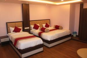 a bedroom with two beds with red pillows at Hotel White Palace Airport Kathmandu in Pashupatināth