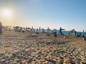 a beach with umbrellas and people on the sand at فيلا بقريه جرين بيتش 4 غرف وحمام سباحة خاص تشطيب السنه فرش مودرن in El Alamein