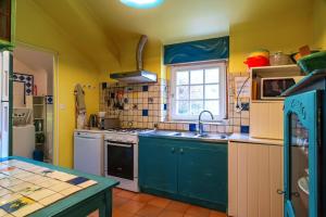a kitchen with blue cabinets and a sink and a window at Ty Océane 2 - 5min du Port dEtel in Étel