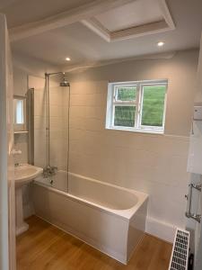 ein weißes Badezimmer mit Badewanne und Waschbecken in der Unterkunft Pretty 2 Bedroom Cottage in Skirmett with Parking in Turville