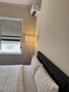 a bedroom with a bed with a lamp and a window at Brand new bedroom next to train station in St Albans
