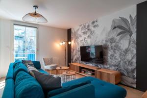 a living room with a blue couch and a tv at Le Méaban - Au cœur de Vannes in Vannes