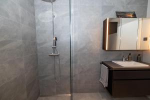 アークレイリにあるLL Properties - Stylish Apartment in Akureyriの洗面台と鏡付きのシャワーを備えたバスルーム