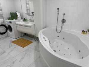 a white bathroom with a tub and a washing machine at M B Homes Lauterstein 8 in Weißenstein