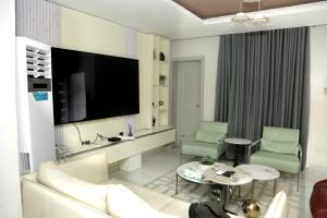 een woonkamer met een bank en een flatscreen-tv bij Lushville Hotels and Suites and Apartments in Benin City