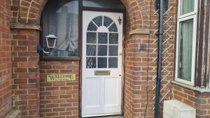 a white door on a brick building with a window at Room Only Booking in Bedford