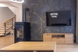 ein Wohnzimmer mit einem TV und einem Kamin in der Unterkunft Przestrony apartament z trzema sypialniami - jacuzzi i parking, kącik zabaw dla dzieci w cenie - świetny wybór dla rodzin lub grupy znajomych in Szczawnica