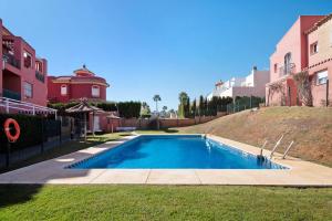 a swimming pool in a yard next to some buildings at Duplex Luminoso Campo de Golf in Islantilla