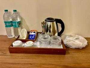 a tray with a tea kettle and cups and water bottles at RG SUITES Formerly RAJ RESIDENCY Near US EMBASSY & APOLLO HOSPITAL in Chennai