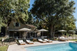a swimming pool with chairs and umbrellas next to a house at La Bastide de Monique - Maison d'hôtes en Provence in Flassans-sur-Issole