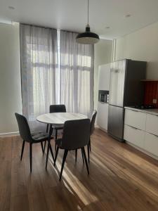 Una cocina con mesa y sillas y un refrigerador. en NovaHome Aktobe, en Aktobe