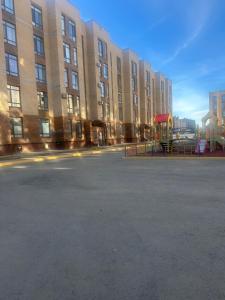 un aparcamiento vacío frente a un gran edificio en NovaHome Aktobe, en Aktobe