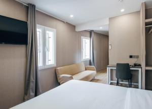 a room with a bed and a desk and chairs at Hotel Golden Madrid in Madrid