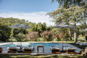 a group of chairs and umbrellas next to a pool at La Bastide de Monique - Maison d'hôtes en Provence in Flassans-sur-Issole