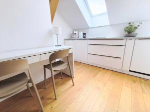 波普拉德Apartment Poprad - Tatra Elegant, Near High Tatras, Free Parking, Modern Stay的配有白色橱柜、桌子和椅子的厨房