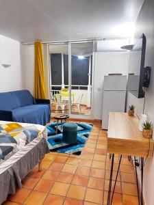 ein Wohnzimmer mit einem blauen Sofa und einem Fernseher in der Unterkunft Studio SUCRIER TARTANE in La Trinité