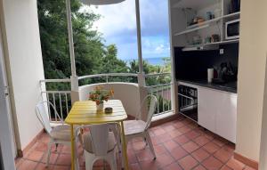 eine Küche mit einem Tisch und Stühlen auf dem Balkon in der Unterkunft Studio SUCRIER TARTANE in La Trinité