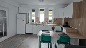 a kitchen with white cabinets and a table with green chairs at Casa Magurele 4 in Măgurele