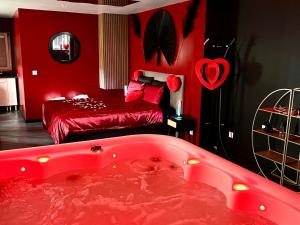 a red room with a tub and a bed at Redroom, Spa, Sauna, cheminée, romantique pour 2 in Quimperlé
