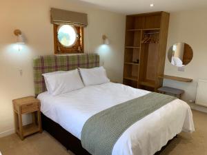 una camera da letto con un grande letto bianco con una finestra di Suilven Cottage a Tain