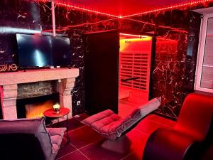 a living room with a fireplace and red lighting at Redroom, Spa, Sauna, cheminée, romantique pour 2 in Quimperlé